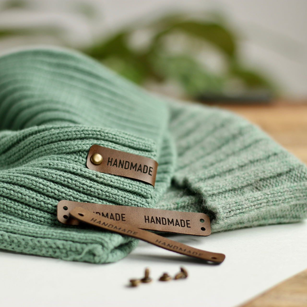 Handmade tag attached to a beanie with bronze snap rivets for easy and convenient attachment.