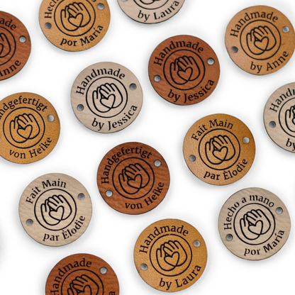 Collection of leather tags with engraved text and logos on a white background